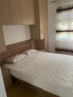 a bedroom with a large white bed with a window at BS Apartman in Podgorica