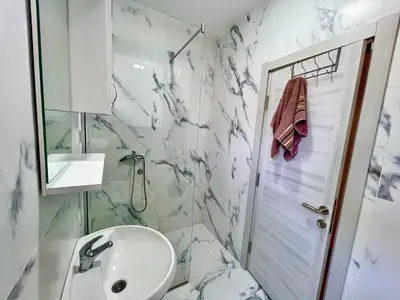 a white bathroom with a sink and a shower at BS Apartman in Podgorica