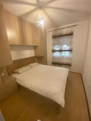 a bedroom with a white bed and a window at BS Apartman in Podgorica