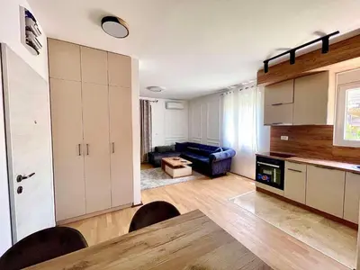 a kitchen and living room with a table and a couch at BS Apartman in Podgorica