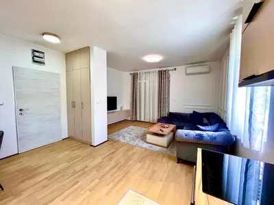 a living room with a blue couch and a television at BS Apartman in Podgorica