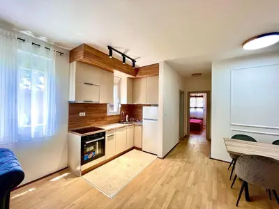 a kitchen with white appliances and a wooden floor at BS Apartman in Podgorica