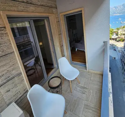 a balcony with two white chairs and a view of a bedroom at Apartman Ema in Budva