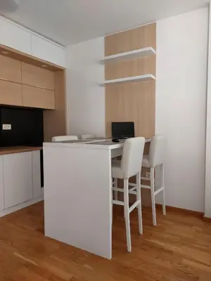a kitchen with a white counter and a table with chairs at Apartman Ema in Budva