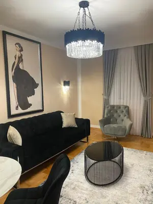 a living room with a black couch and a chandelier at Two bedroom lux apartment in Budva