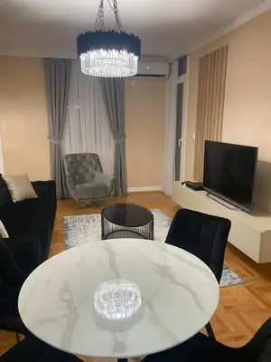 a living room with a white table and a tv at Two bedroom lux apartment in Budva