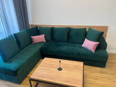 a green couch with two pink pillows and a coffee table at Apartman Sun in Ulcinj