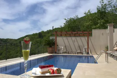 a glass of juice and cake on a table next to a pool at Luxury Villa Flower in Budva