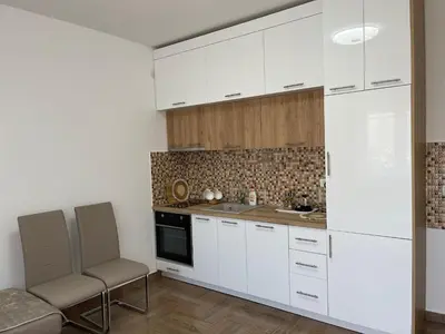 a kitchen with white cabinets and a table and chairs at Villa Sunshine in Bar