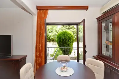 a dining room with a table and a window at Apartment Nikolija in Dobrota