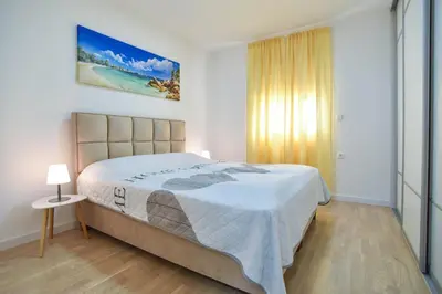a bedroom with a large bed with a white blanket at LUX Apartment TEAM JOKIC in Becici