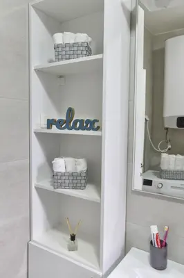 a bathroom shelf with towels and a mirror at LUX Apartment TEAM JOKIC in Becici