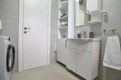 a white bathroom with a sink and a washing machine at LUX Apartment TEAM JOKIC in Becici