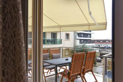 a table and chairs on a balcony with an umbrella at LUX Apartment TEAM JOKIC in Becici