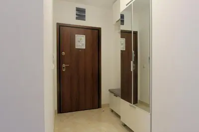 a hallway with a wooden door and a mirror at Anatolija Apartment 11 in Budva