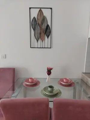 a living room with a glass table with two pink chairs at K2-SistersApartment in Podgorica