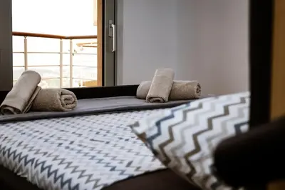 a bedroom with a bed with towels and a mirror at Penthouse TivatHeights Pool & Sea View-B4 in Kavač