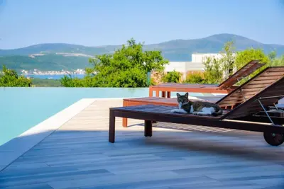 a cat laying on a bench next to a pool at Penthouse TivatHeights Pool & Sea View-B4 in Kavač