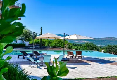 a swimming pool with chairs and umbrellas next to it at Penthouse TivatHeights Pool & Sea View-B4 in Kavač