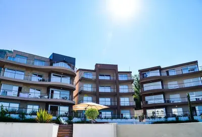 a large apartment building with an umbrella in front of it at Penthouse TivatHeights Pool & Sea View-B4 in Kavač