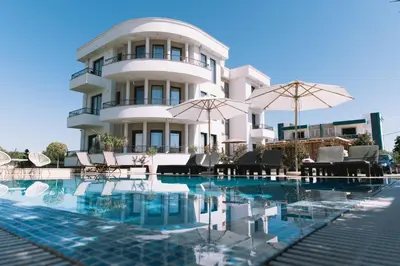 a building with a pool and chairs and umbrellas at Apartments Moon White Lux in Ulcinj