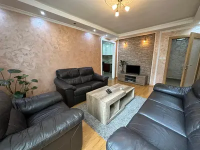a living room with leather couches and a coffee table at Nikki’s Apartment Podgorica in Podgorica