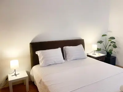 a bedroom with a white bed with two night stands at Nikki’s Apartment Podgorica in Podgorica