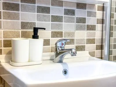 a bathroom sink with a faucet and two rolls of toilet paper at Nikki’s Apartment Podgorica in Podgorica