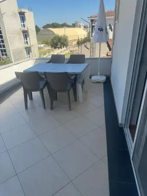 a table and chairs on a balcony with an umbrella at Vila Almas in Ulcinj