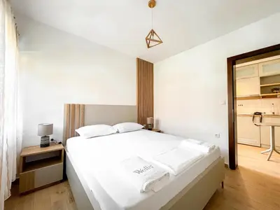 a bedroom with a white bed with white sheets at Higo Apartments in Ulcinj