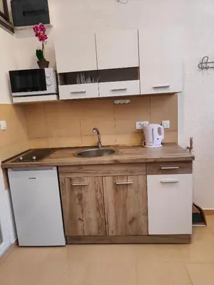 a kitchen with white cabinets and a sink and a refrigerator at Sutorange in Sutomore