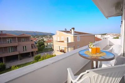 a table on a balcony with a view of a city at NESI Apartments in Ulcinj