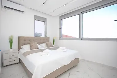 a white bedroom with a large bed and windows at NESI Apartments in Ulcinj