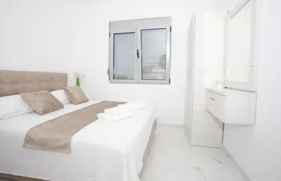 a white bedroom with a large bed and a window at NESI Apartments in Ulcinj