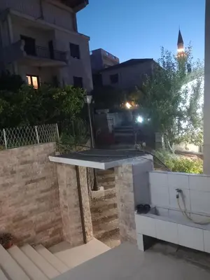 a patio with a table with a cat sitting under it at Ulpiana - Apartments,Rooms,Hostel in Ulcinj