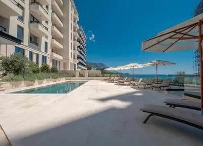 a swimming pool with chairs and umbrellas next to a building at Azure Horizon in Becici