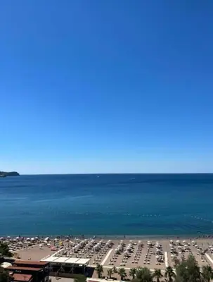 a beach with a lot of cars parked next to the water at Azure Horizon in Becici