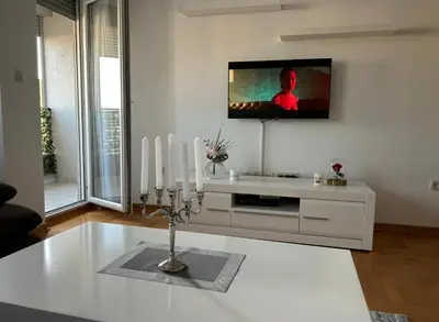 a living room with a tv on the wall and a candlestick at Apartment Shine in Konik