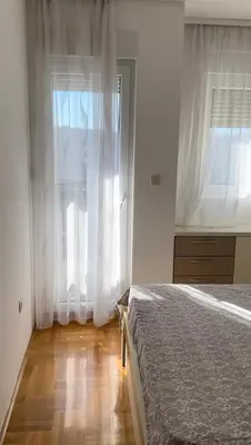 a bedroom with a bed and a window with white curtains at Apartment Shine in Konik