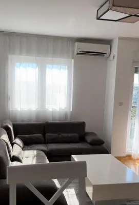 a living room with a black couch and two windows at Apartment Shine in Konik