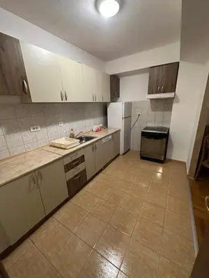 an empty kitchen with white cabinets and a refrigerator at Big apartment 2 in Podgorica