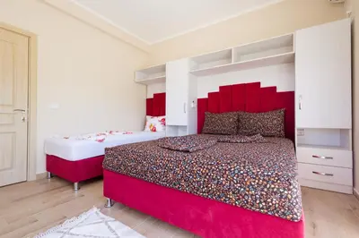a bedroom with two beds and a red headboard at Reis Apartments in Ulcinj