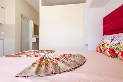 a bed with a pink bedspread and two pillows at Reis Apartments in Ulcinj