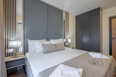 a bedroom with a large white bed with a large headboard at Dulamerovic Hotel in Ulcinj