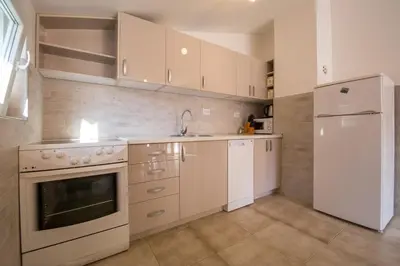 a kitchen with white cabinets and a sink and a refrigerator at Apartments Kovačević in Petrovac na Moru