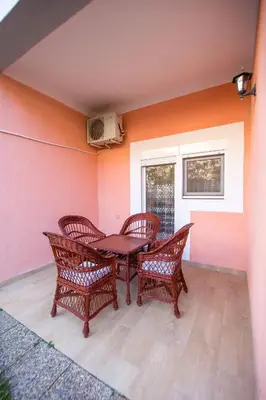 a patio with three wicker chairs and a table at Apartments Kovačević in Petrovac na Moru