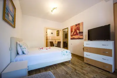 a bedroom with a white bed and a flat screen tv at Apartments Kovačević in Petrovac na Moru