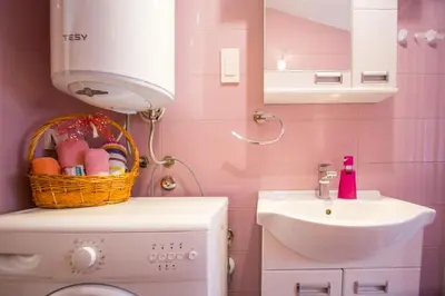 a pink bathroom with a sink and a washing machine at Apartments Kovačević in Petrovac na Moru
