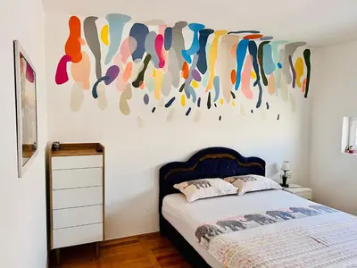 a bedroom with a bed and a painting on the wall at City Center Square DeLuxe Nest in Podgorica