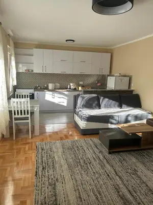 a bedroom with a bed and a table and a kitchen at Prestige in Podgorica